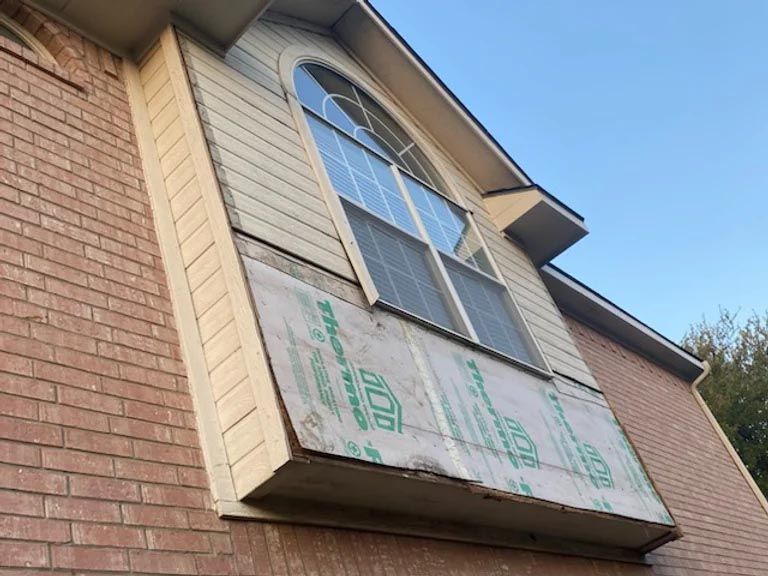 A window on the side of a brick house with a green sticker on it