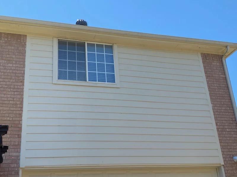 A brick house with a white siding and a window