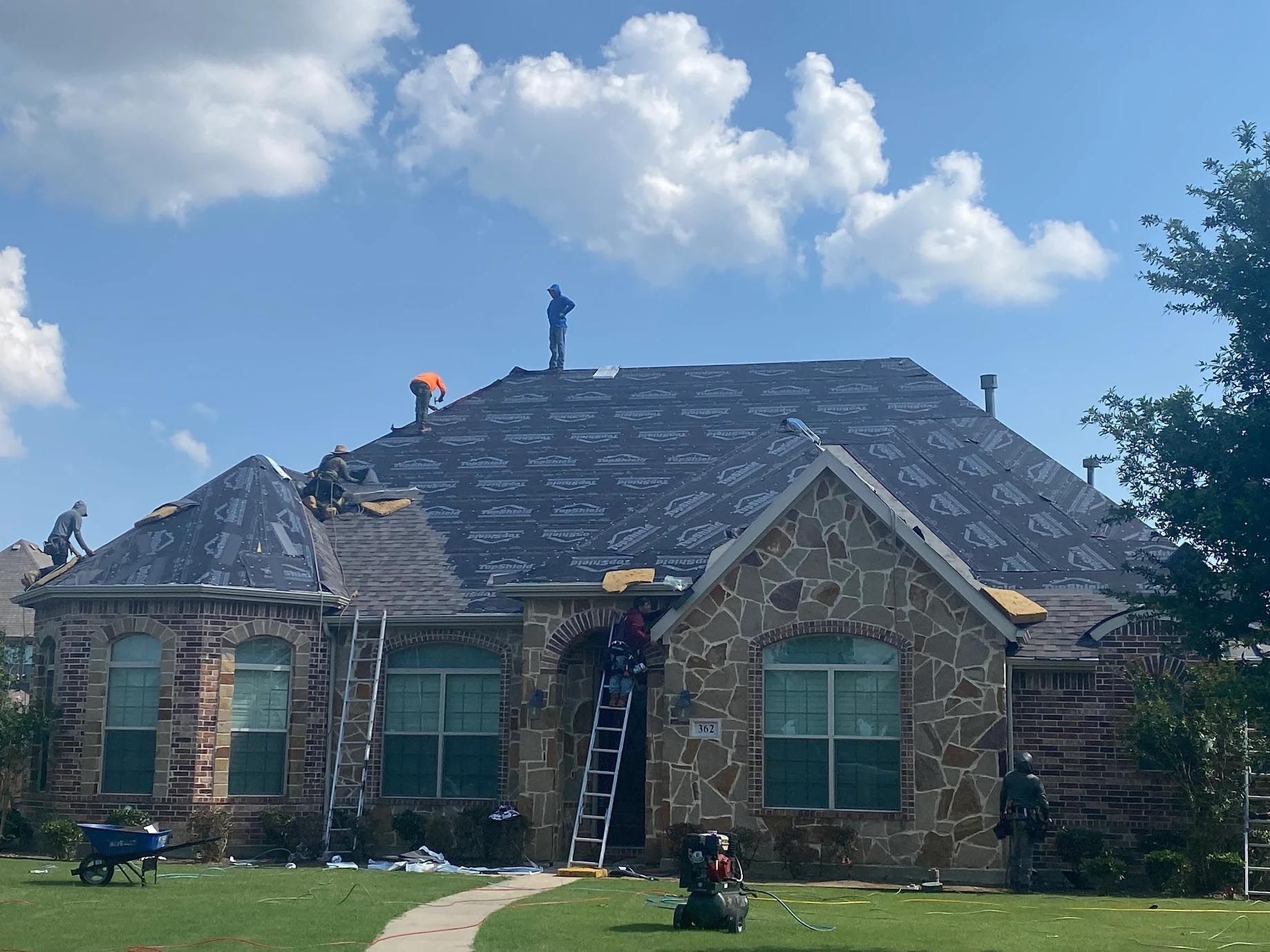 A large stone house is being remodeled with a new roof.