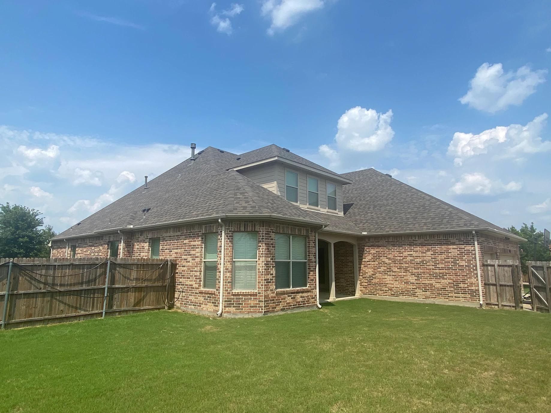 A large brick house with a fence in front of it.