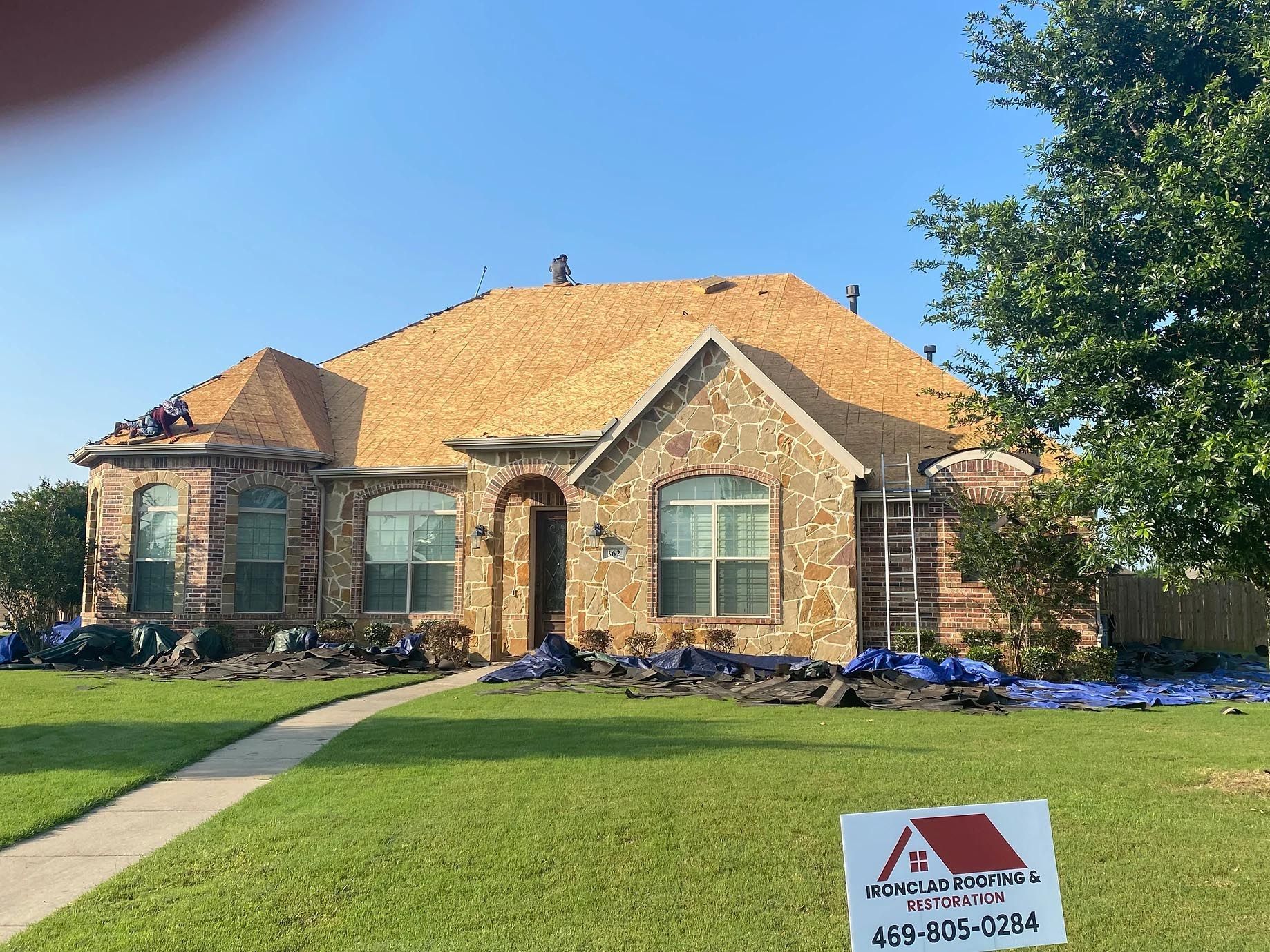 A large brick house with a red roof is being remodeled.