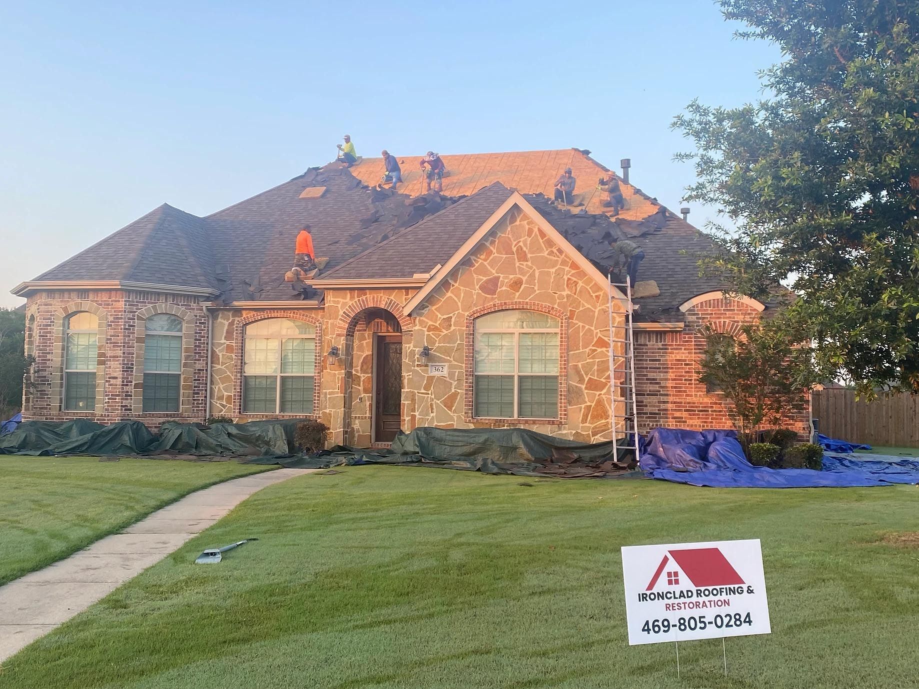 A brick house with a sign in front of it that says roofing.