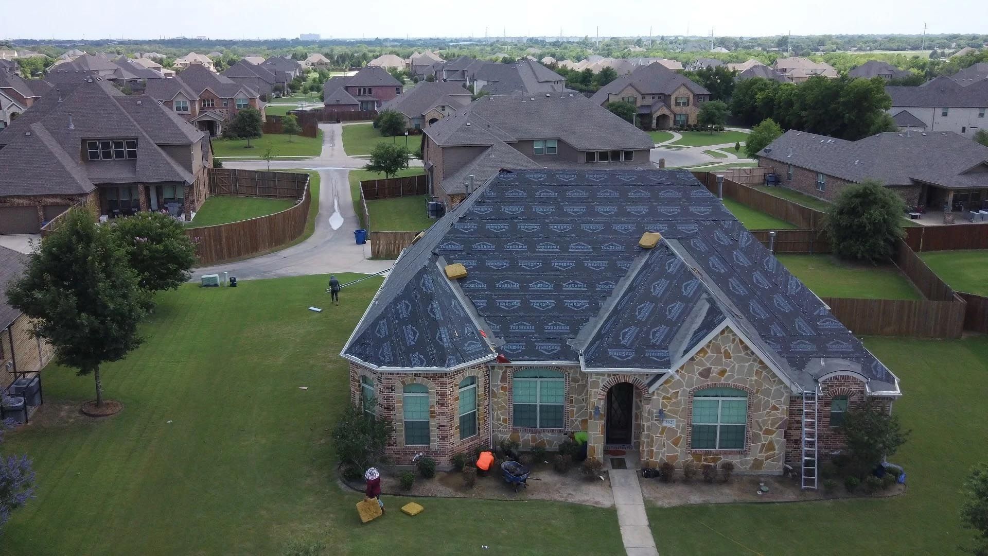 An aerial view of a house with a new roof being installed.