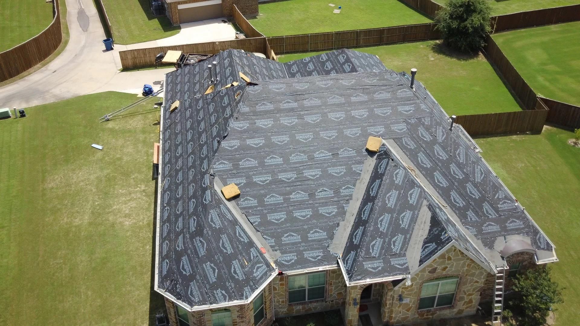 An aerial view of a house with a new roof being installed.