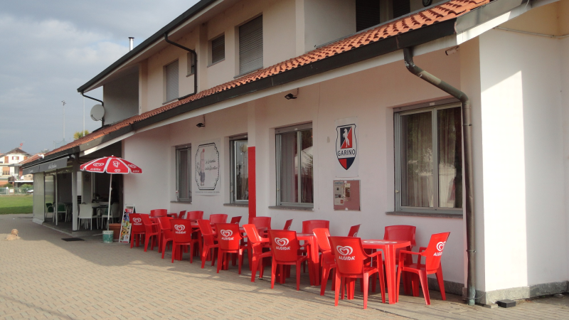 Un edificio bianco con sedie e tavoli rossi all'esterno