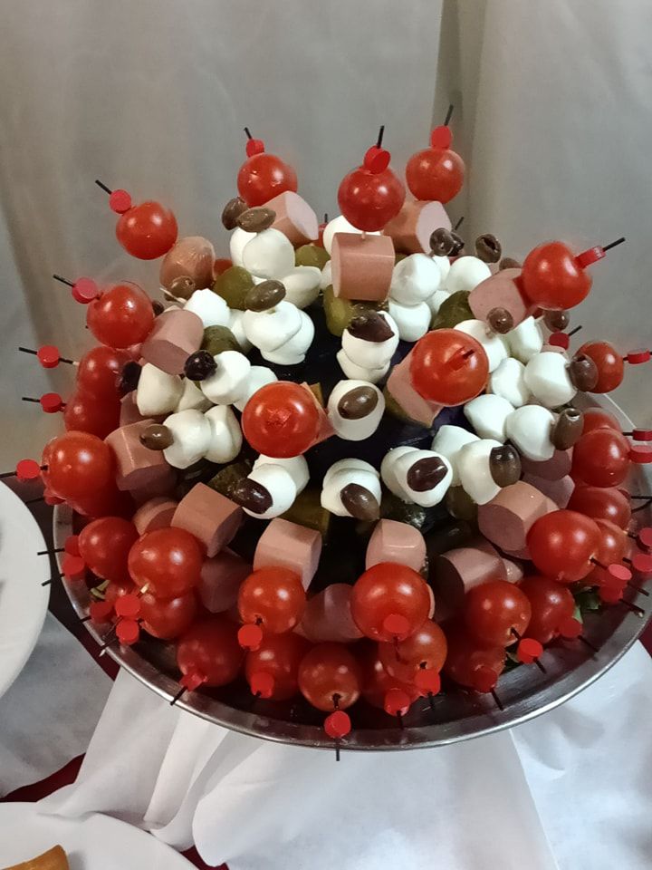 Un piatto di cibo con pomodori, olive e prosciutto su spiedini