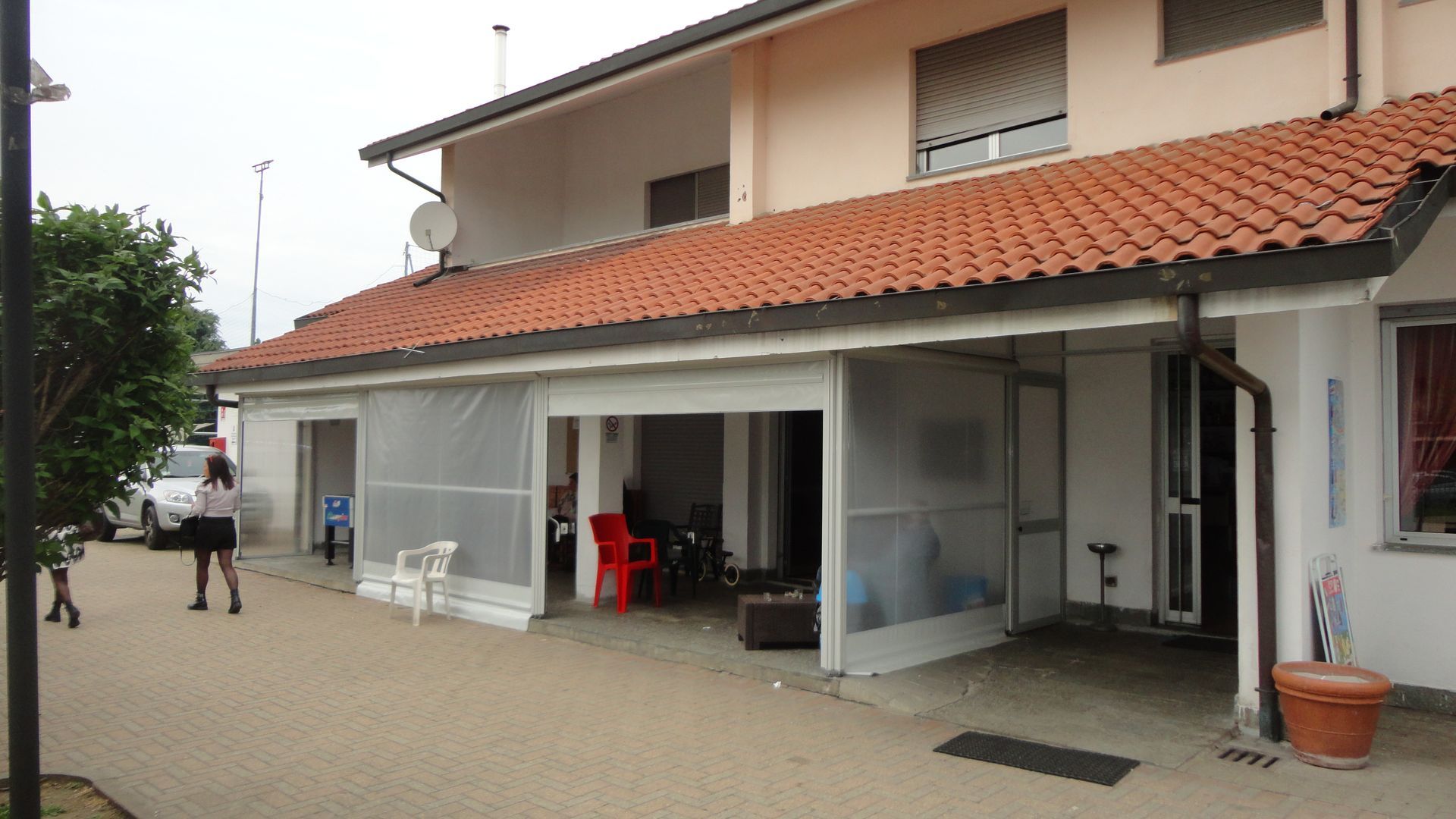 Una donna è in piedi davanti a una casa con un tetto di tegole rosse