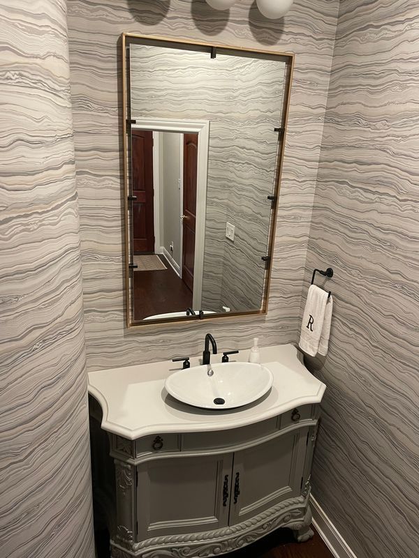 A bathroom with a sink , mirror and towel rack.