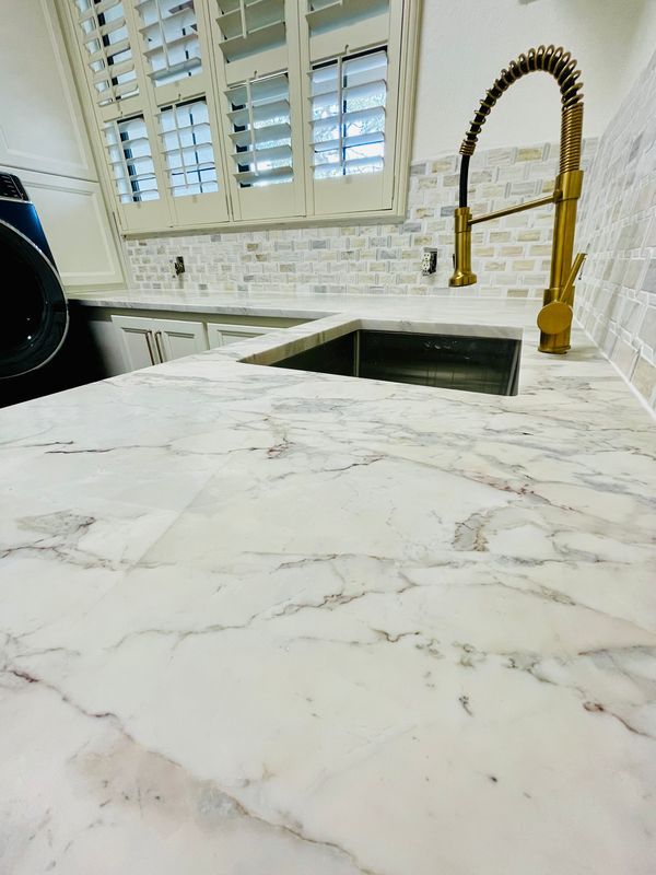 A kitchen with a sink and a marble counter top
