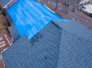 An aerial view of a roof with a blue tarp on it.