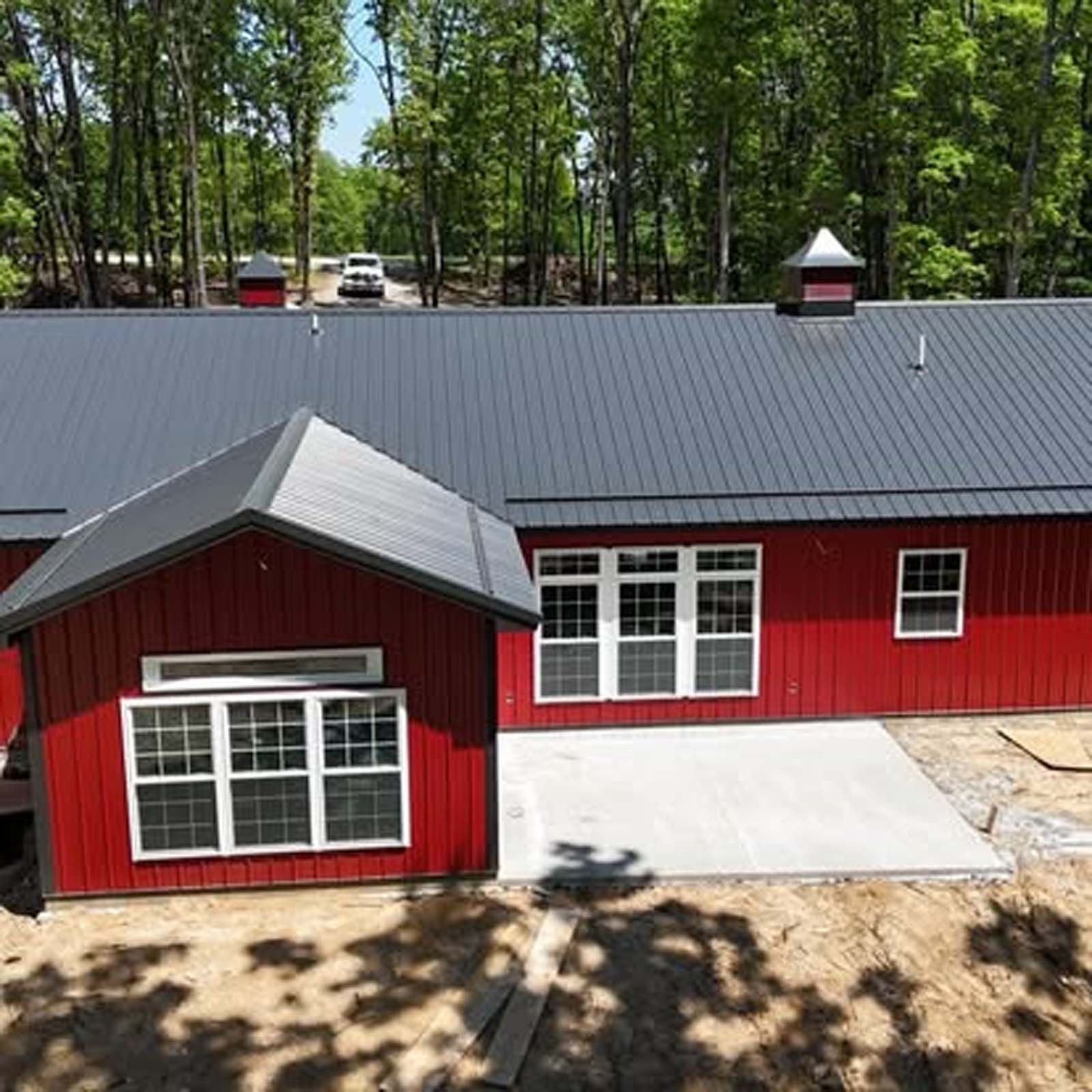 An aerial view of a red house with a black roof surrounded by trees.