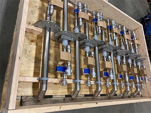 A wooden box filled with stainless steel pipes and valves.