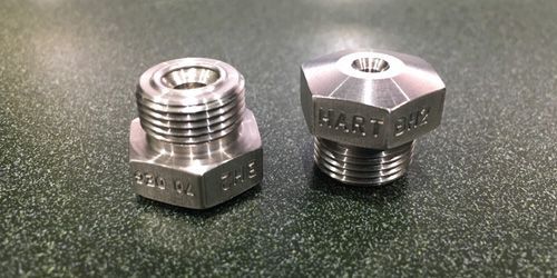 Two stainless steel nuts are sitting next to each other on a table.