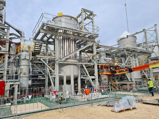 A large industrial plant is being built with a crane in the foreground.