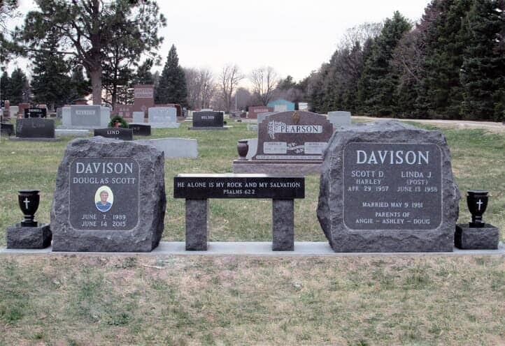 Rustic boulder memorials and bench in black granite with turned vases on pedestals