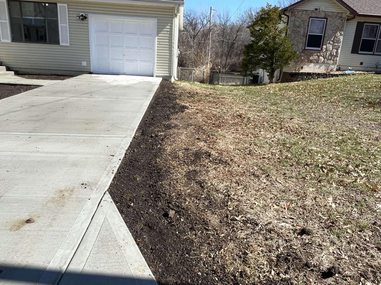A concrete driveway leading to a house with a white garage door.