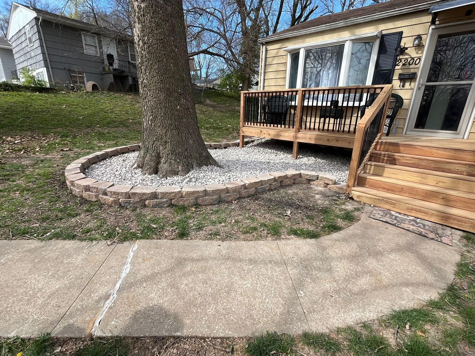 A house with a deck and stairs next to a tree.