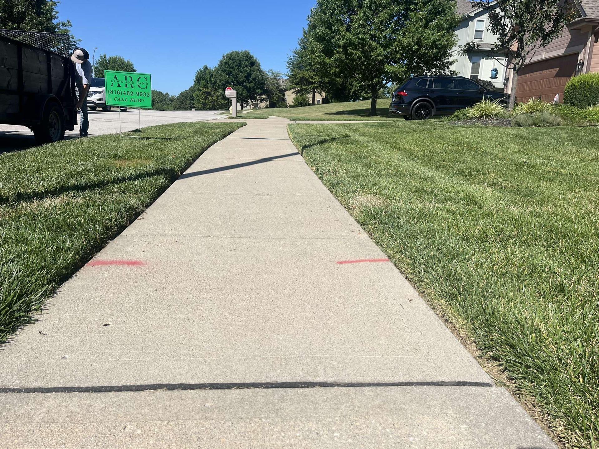 A sidewalk with a green sign on the side of it.