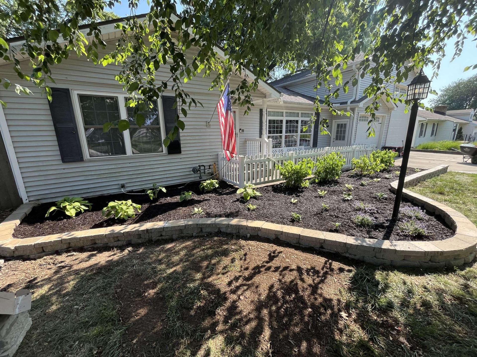 A garden in front of a house with a flag in the background.
