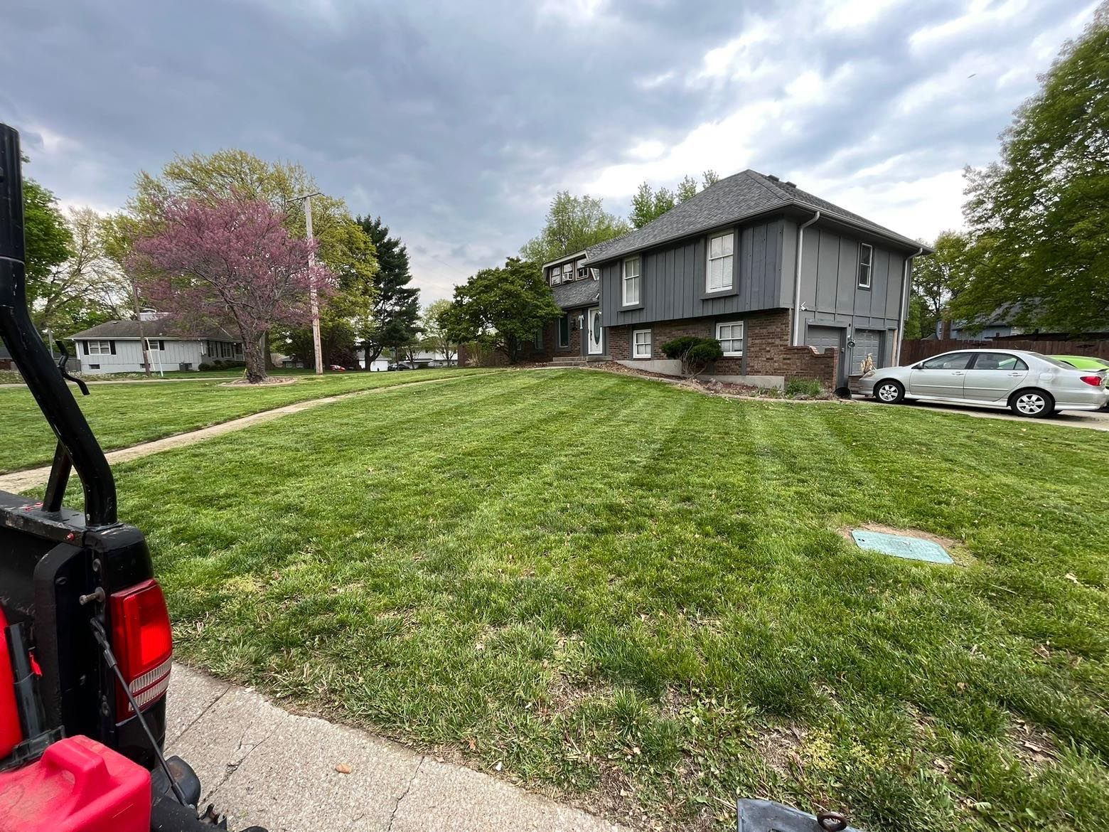 A red atv is parked in front of a lush green lawn in front of a house.