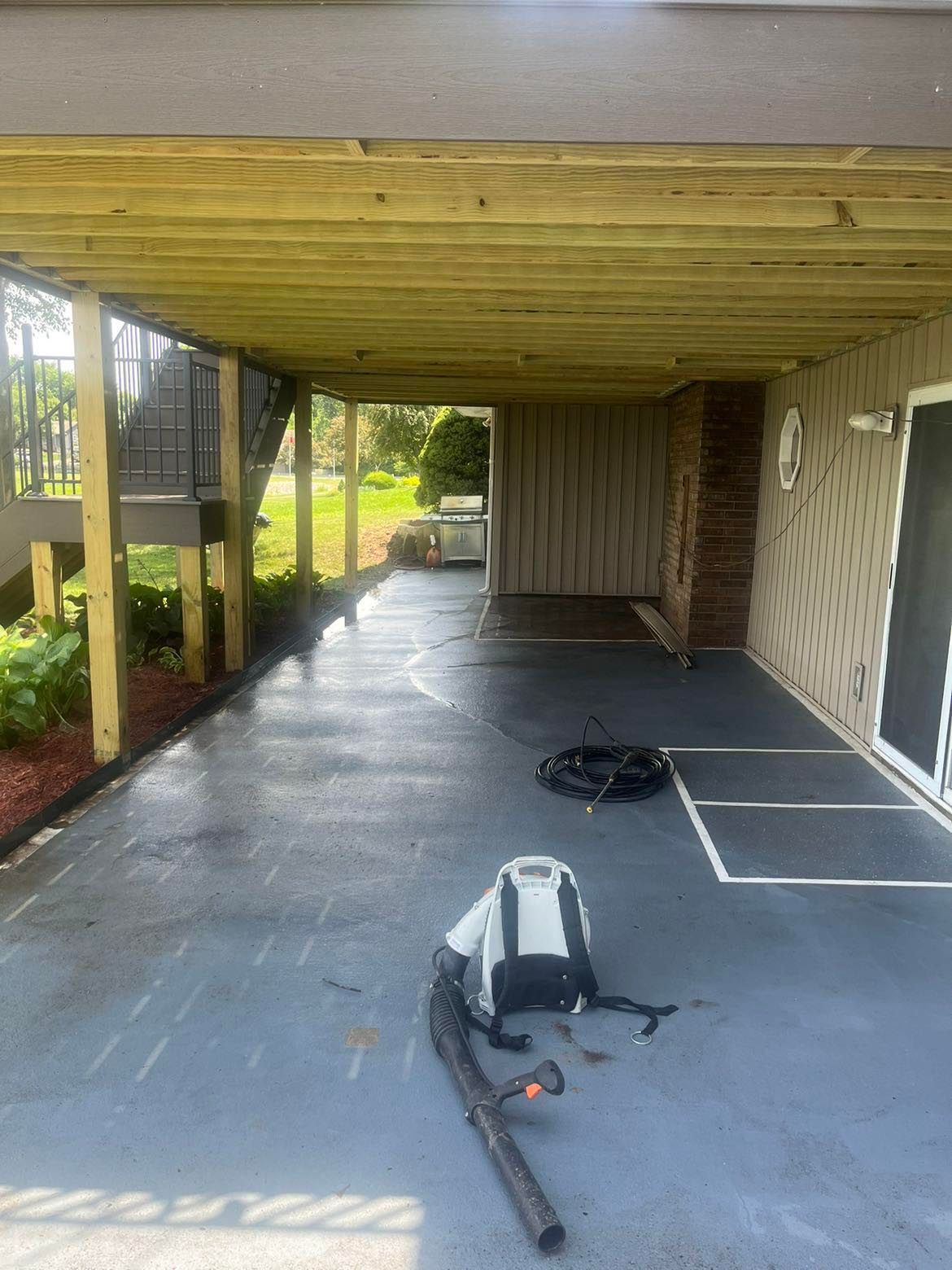 A vacuum cleaner is sitting on the ground under a wooden deck.