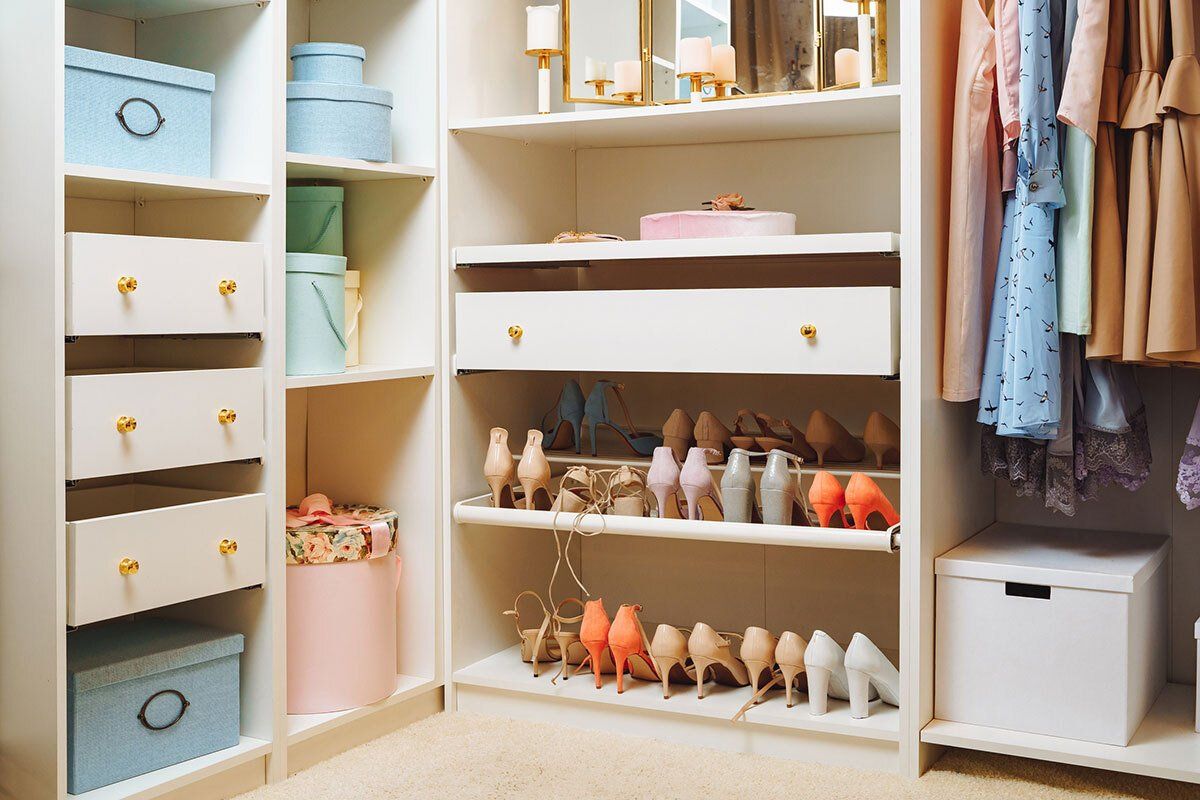 Walk-in closet with organized shelves and drawers; clothing, shoes, and boxes neatly arranged.