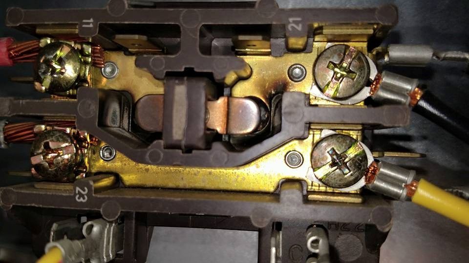 Close-up of electrical relay terminals with burned contacts. Wires are attached.