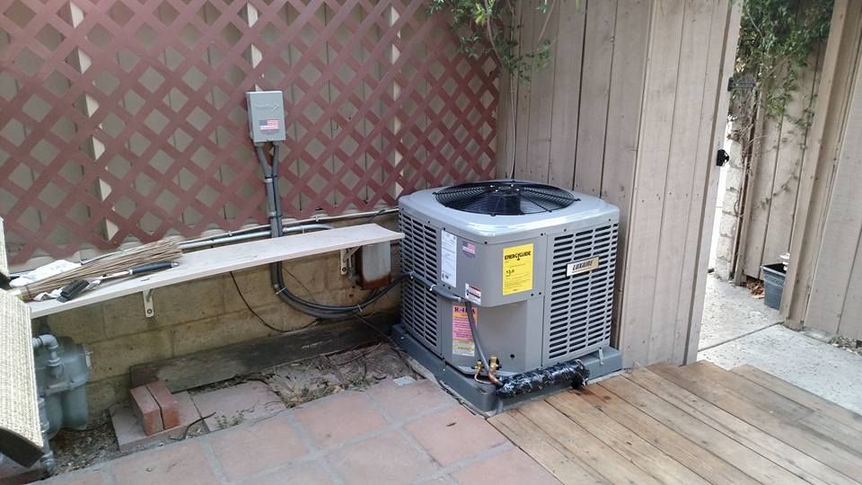 AC unit next to a lattice fence, wood deck, and electrical box.