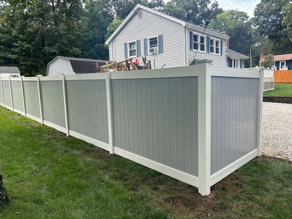 A gray and white vinyl fence is in front of a house.