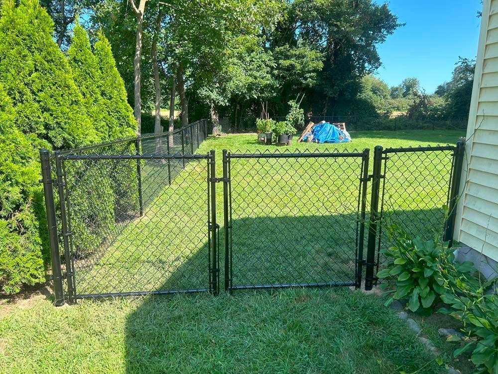 A chain link fence with a gate in the backyard of a house.