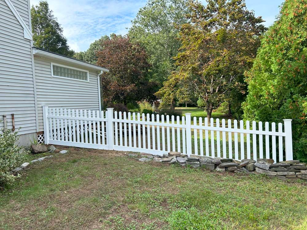 A white picket fence is in the backyard of a house.