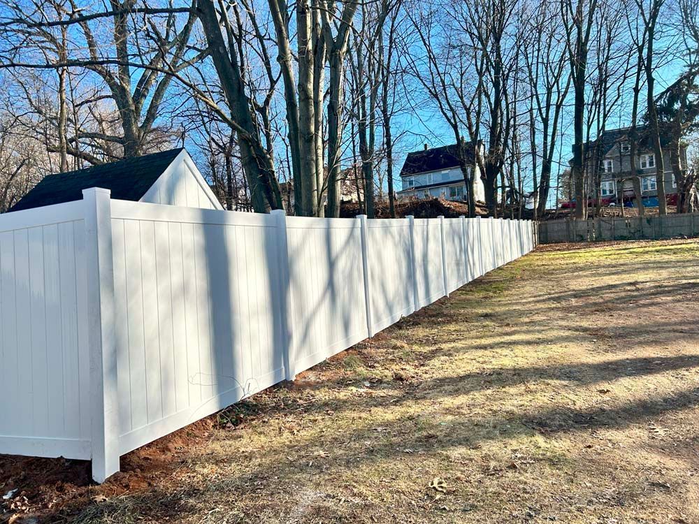 A long white fence surrounds a lush green field.