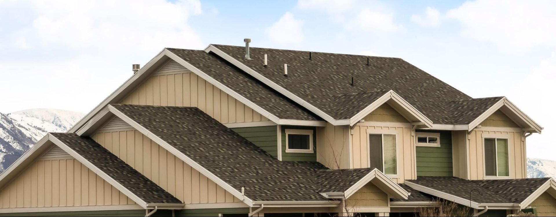 A large house with a gray roof and a blue sky in the background.