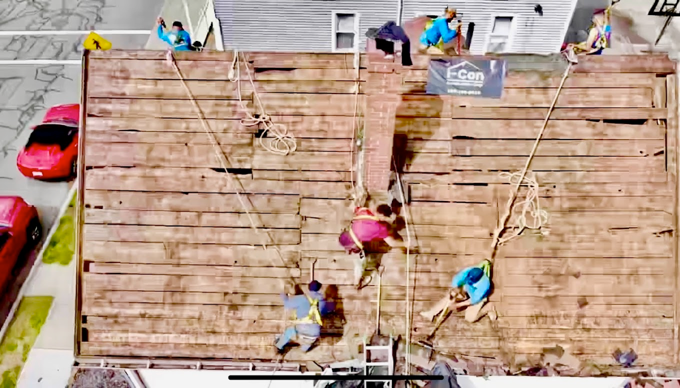 People climbing a wooden wall with ropes in an outdoor setting, aerial view.