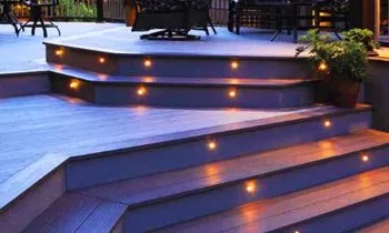 A deck with stairs that are lit up at night.
