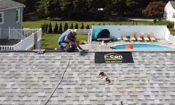 Man on roof repairing shingles near a pool. E-Con sign visible.