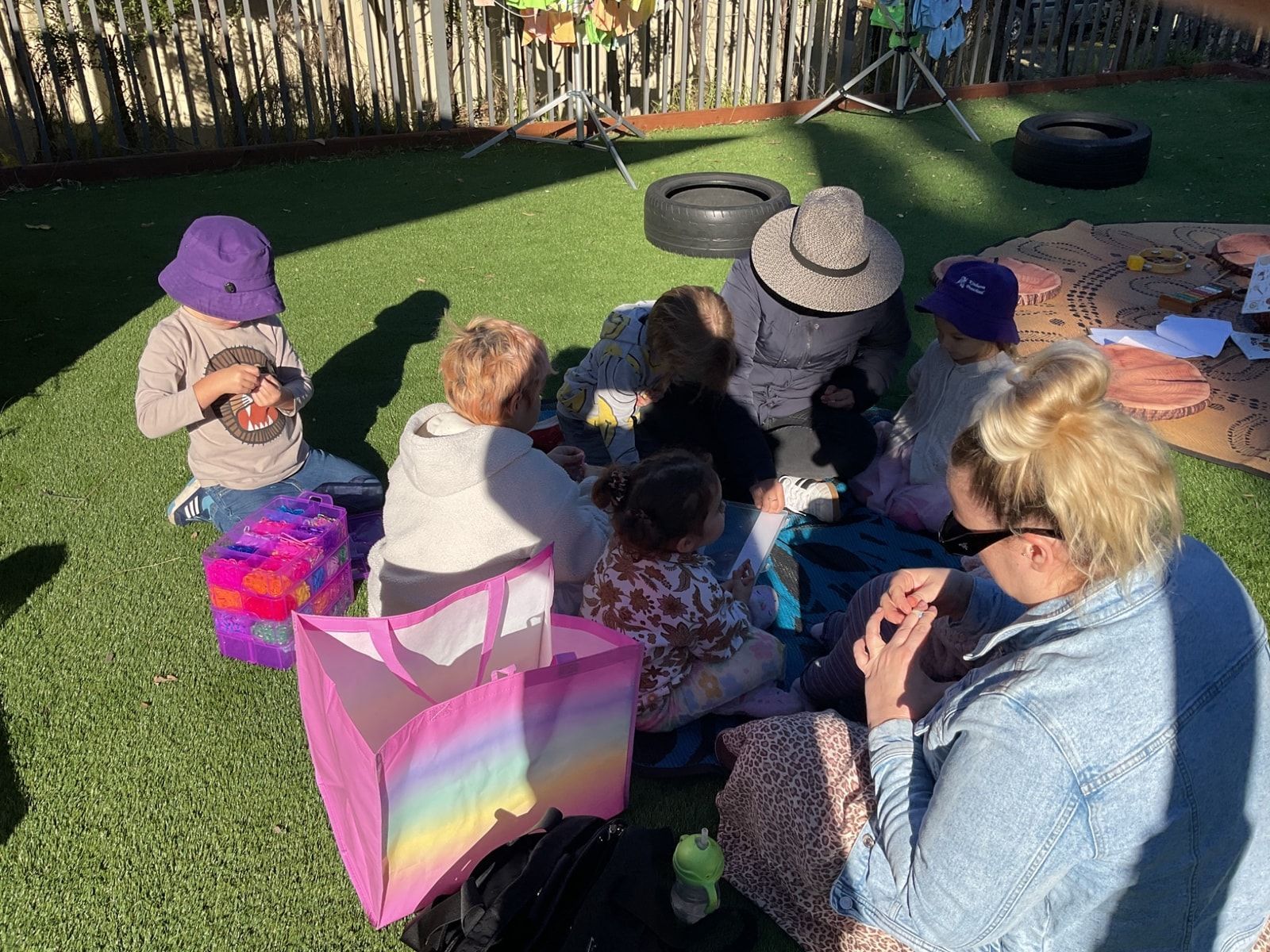 Children and adults sit on grass — Kinburra Preschool (Kincumber) in Kincumber, NSW