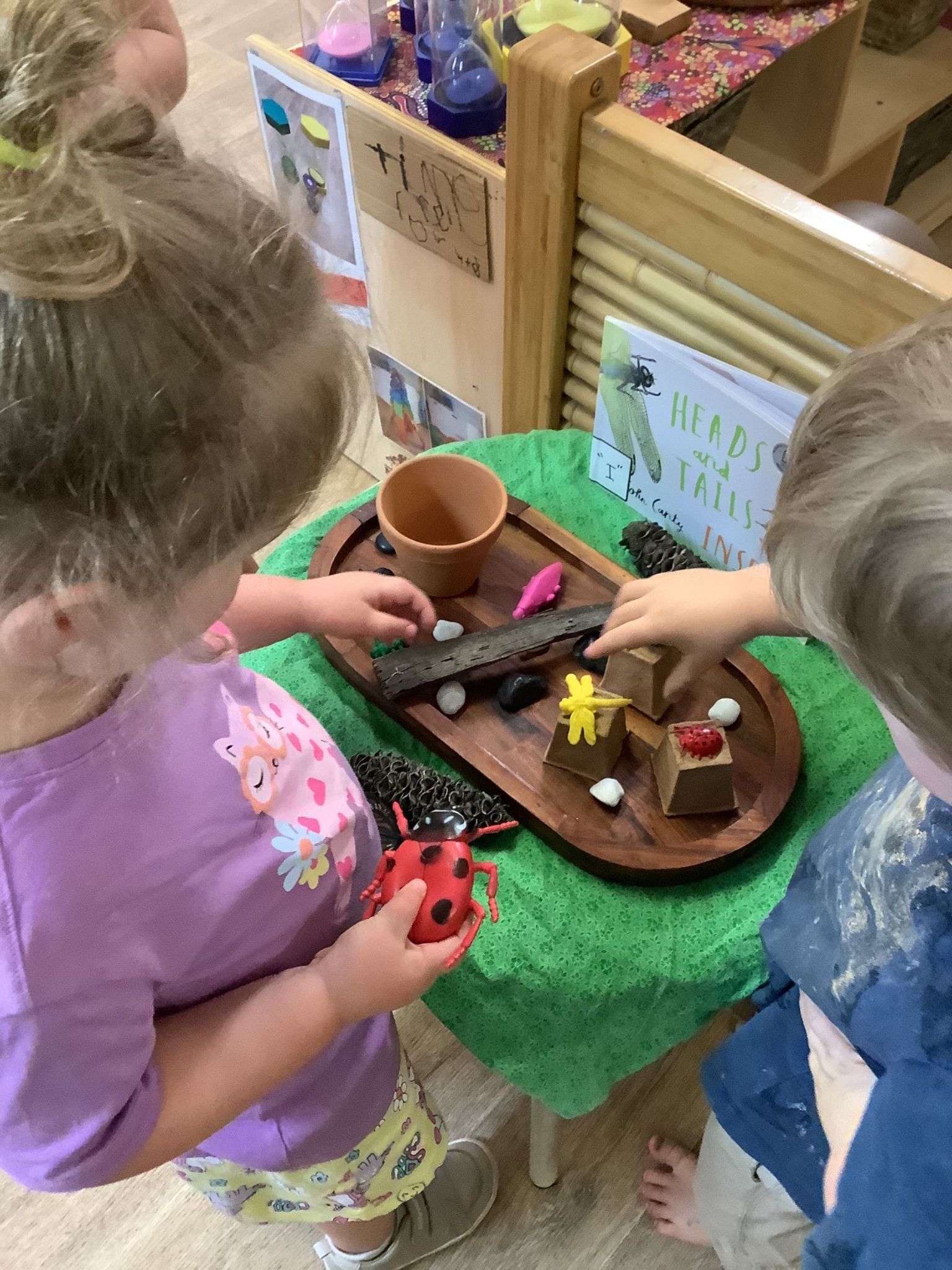 Two young children playing with toys on a wooden tray, exploring a nature-themed setup  — Kinburra Preschool (Kincumber) in Kincumber, NSW