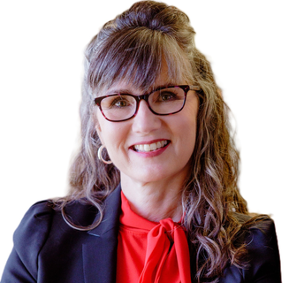 A woman in a tan jacket and white shirt is standing in front of a white background.