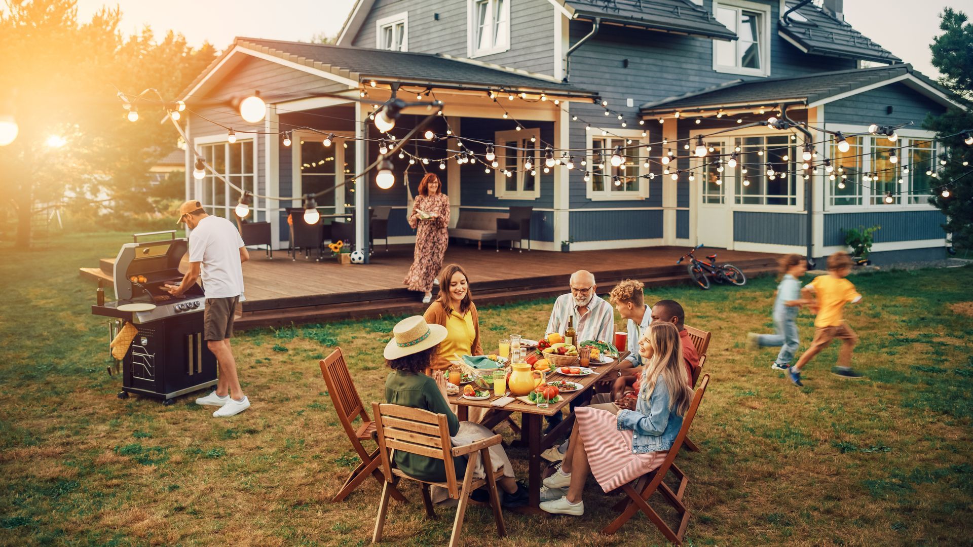 A group of people are sitting around a table in front of a house.