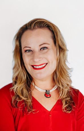 A woman in a red shirt and necklace is smiling for the camera.