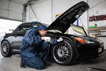 mechanic repairing black nissan sports car