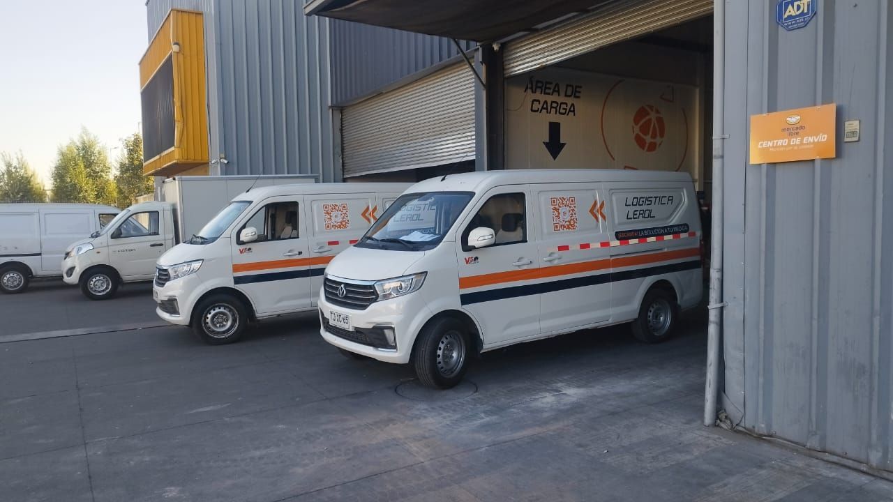 Dos furgonetas blancas están estacionadas una al lado de la otra frente a un edificio.