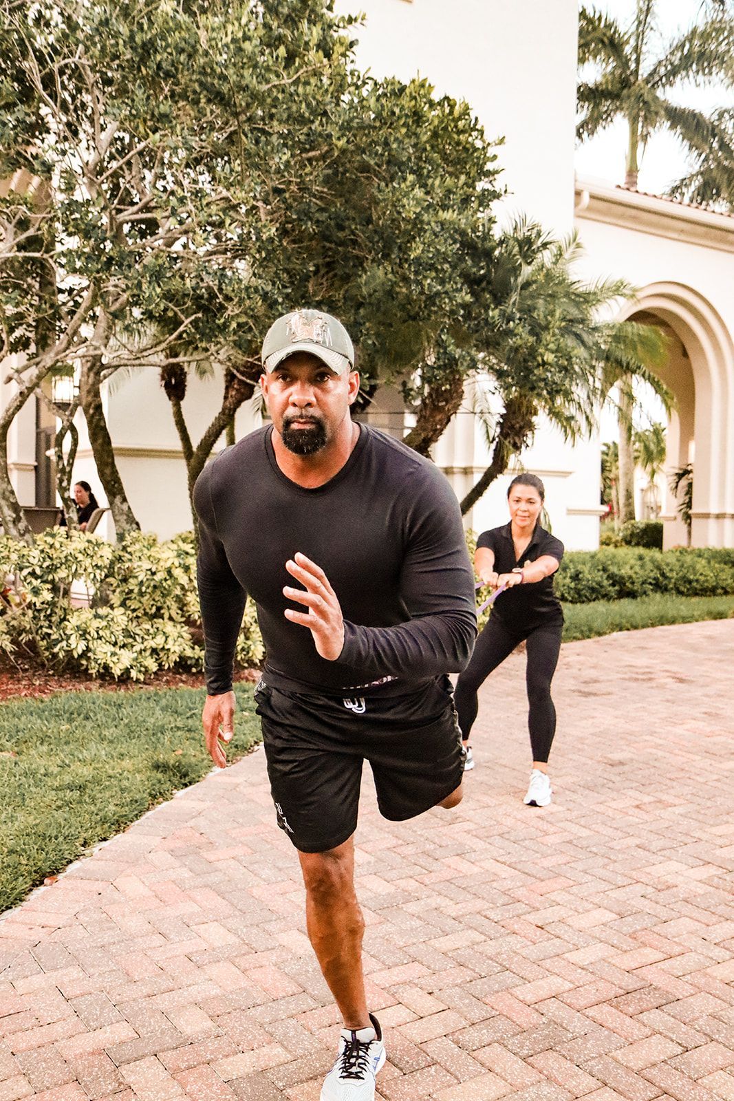 A man and a woman are running on a sidewalk.