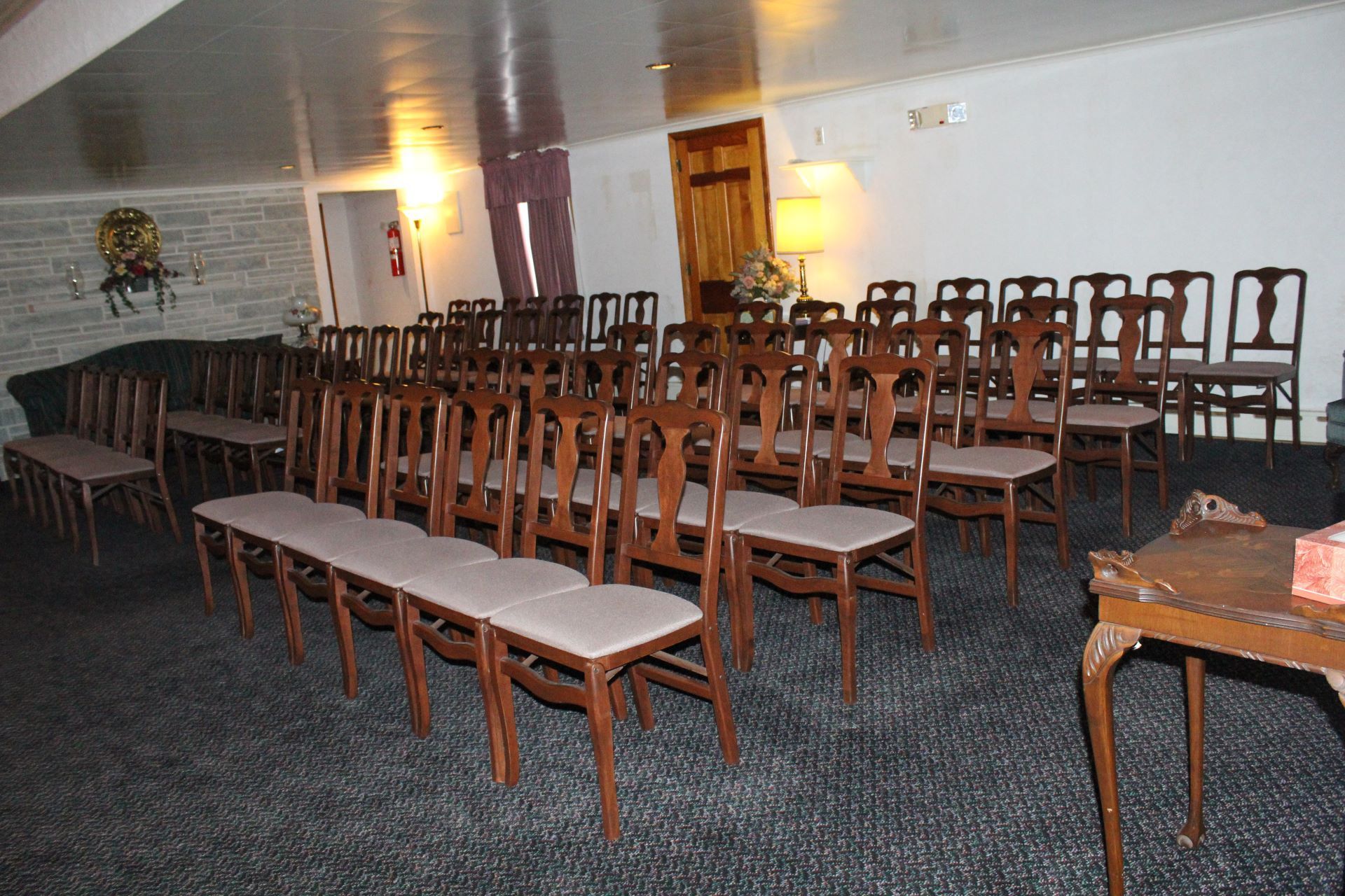 Rows of wooden chairs are lined up in a room.