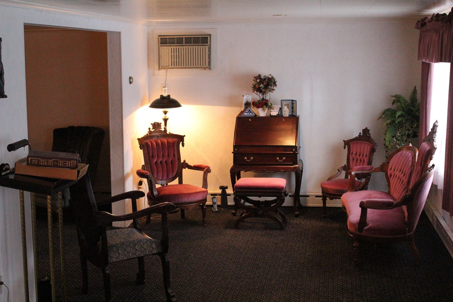 A living room with chairs a desk and a lamp