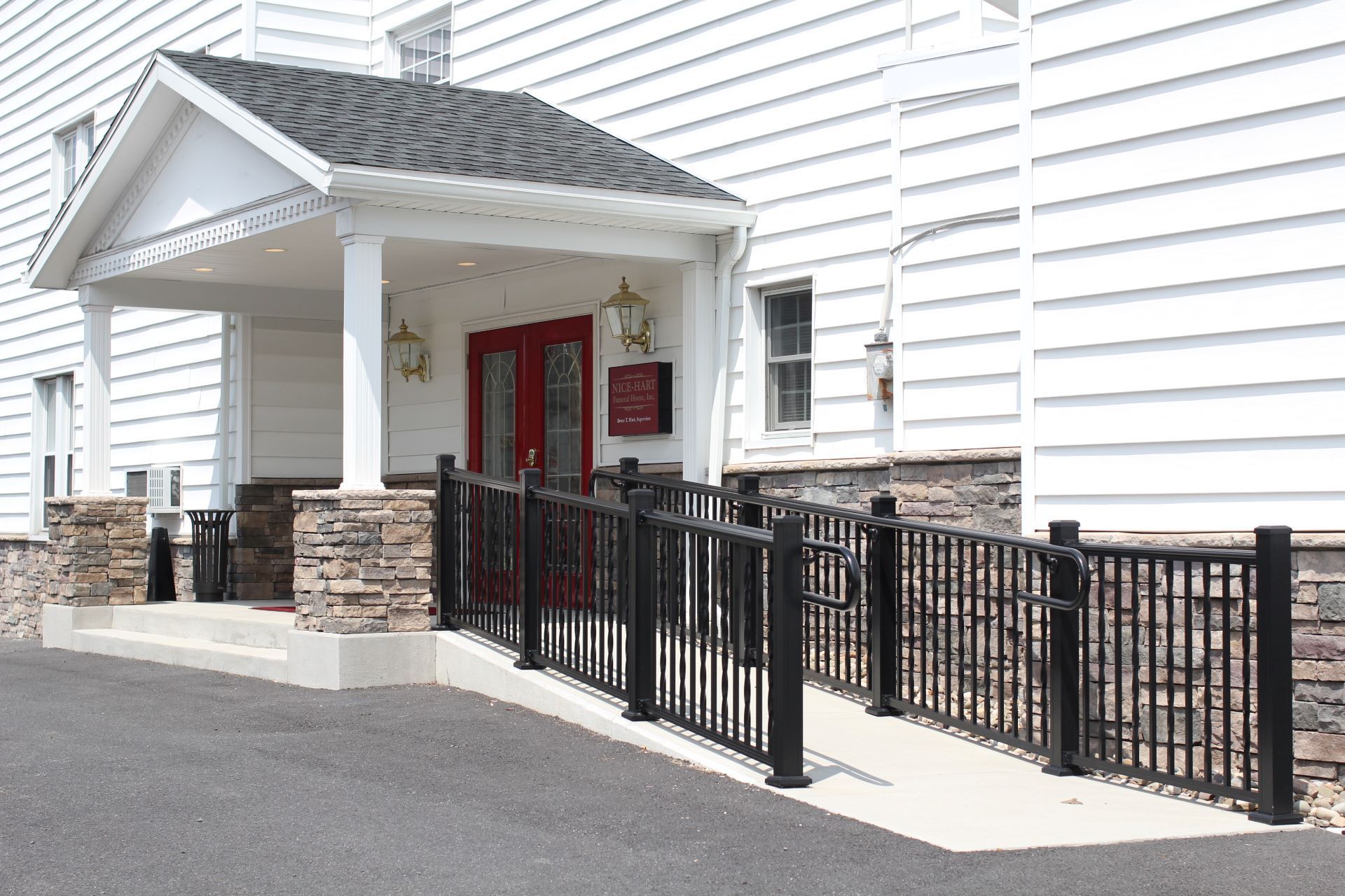 A white house with a red door and a black fence