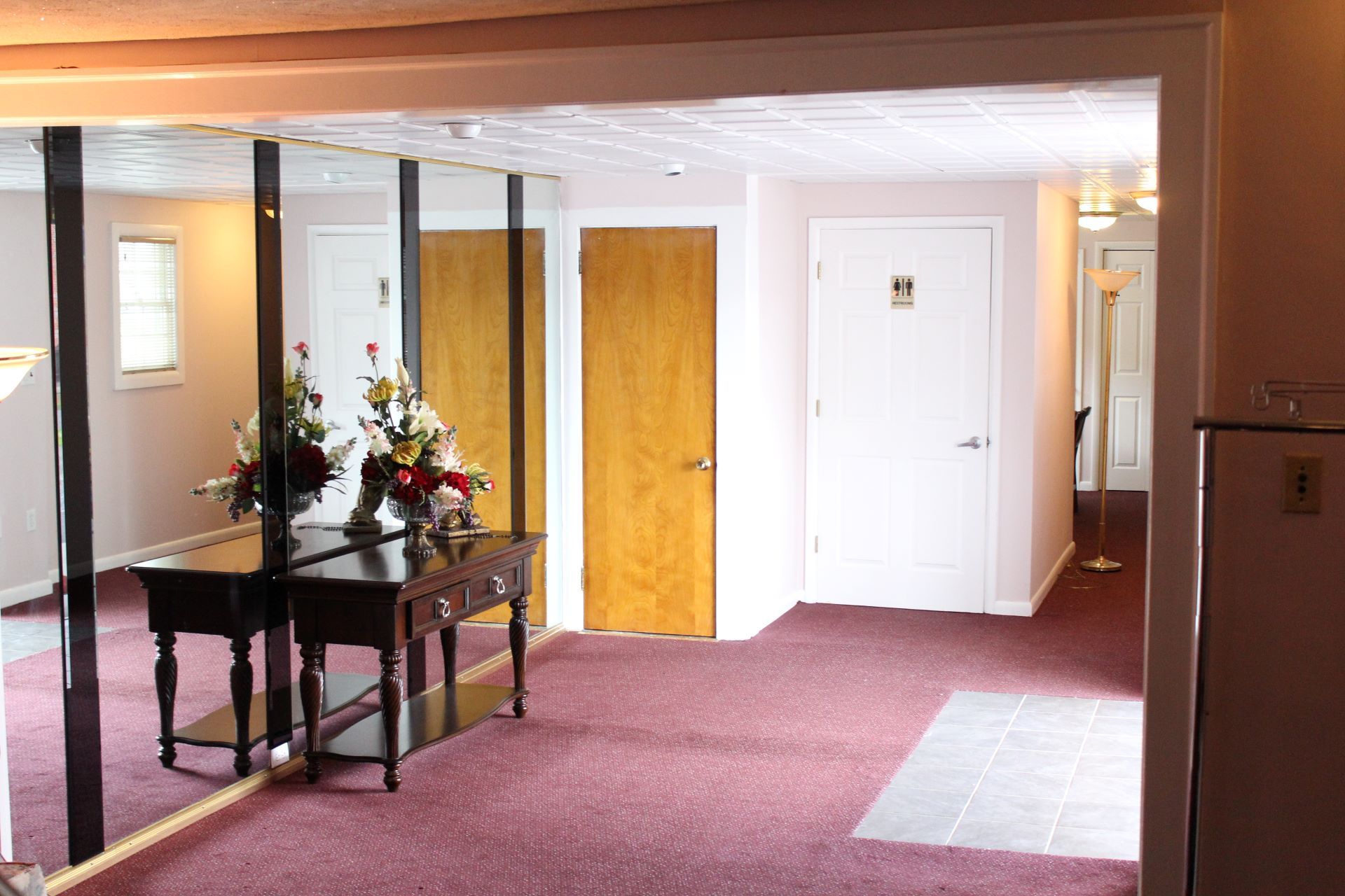 A hallway with mirrors and a table with flowers on it
