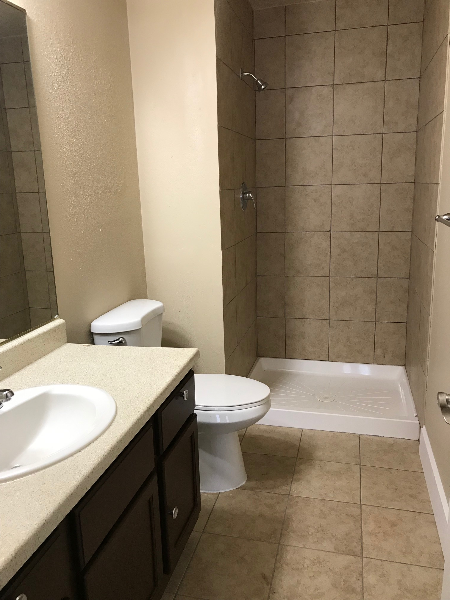 Bathroom with a vanity, toilet, and tiled shower.