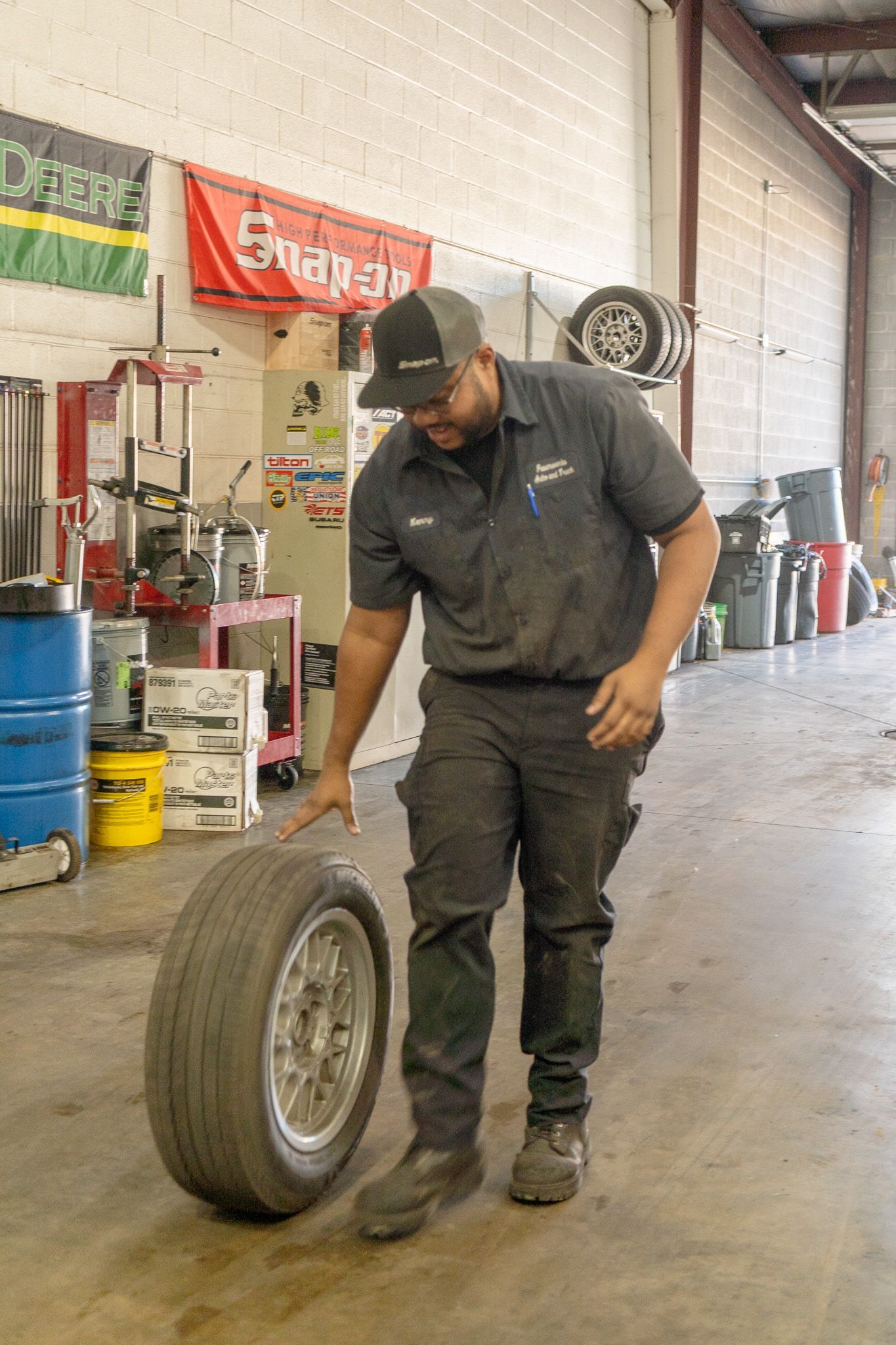 Mechanic in a Garage, Rolling a Tire and Wheel Assembly | FauerWerks Auto & Truck